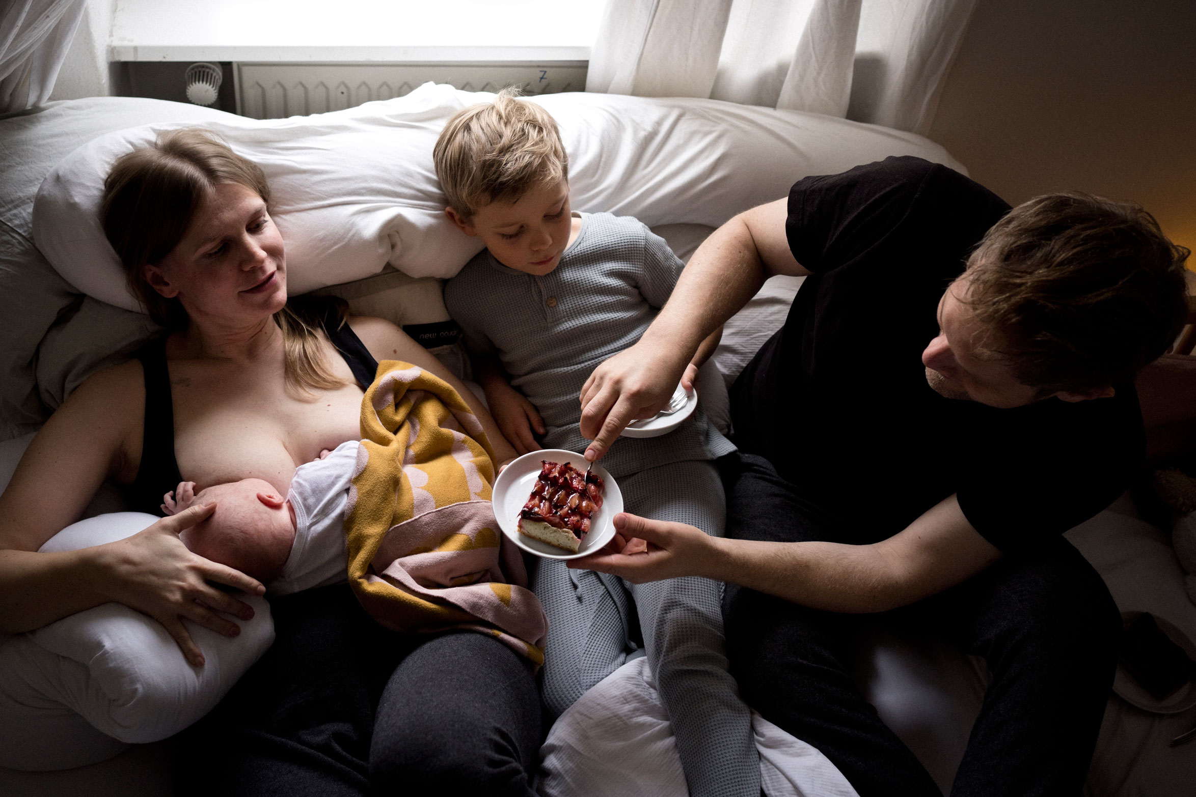 Neugeborenenfotos Berlin _ Mann füttert Frau im Wochenbett