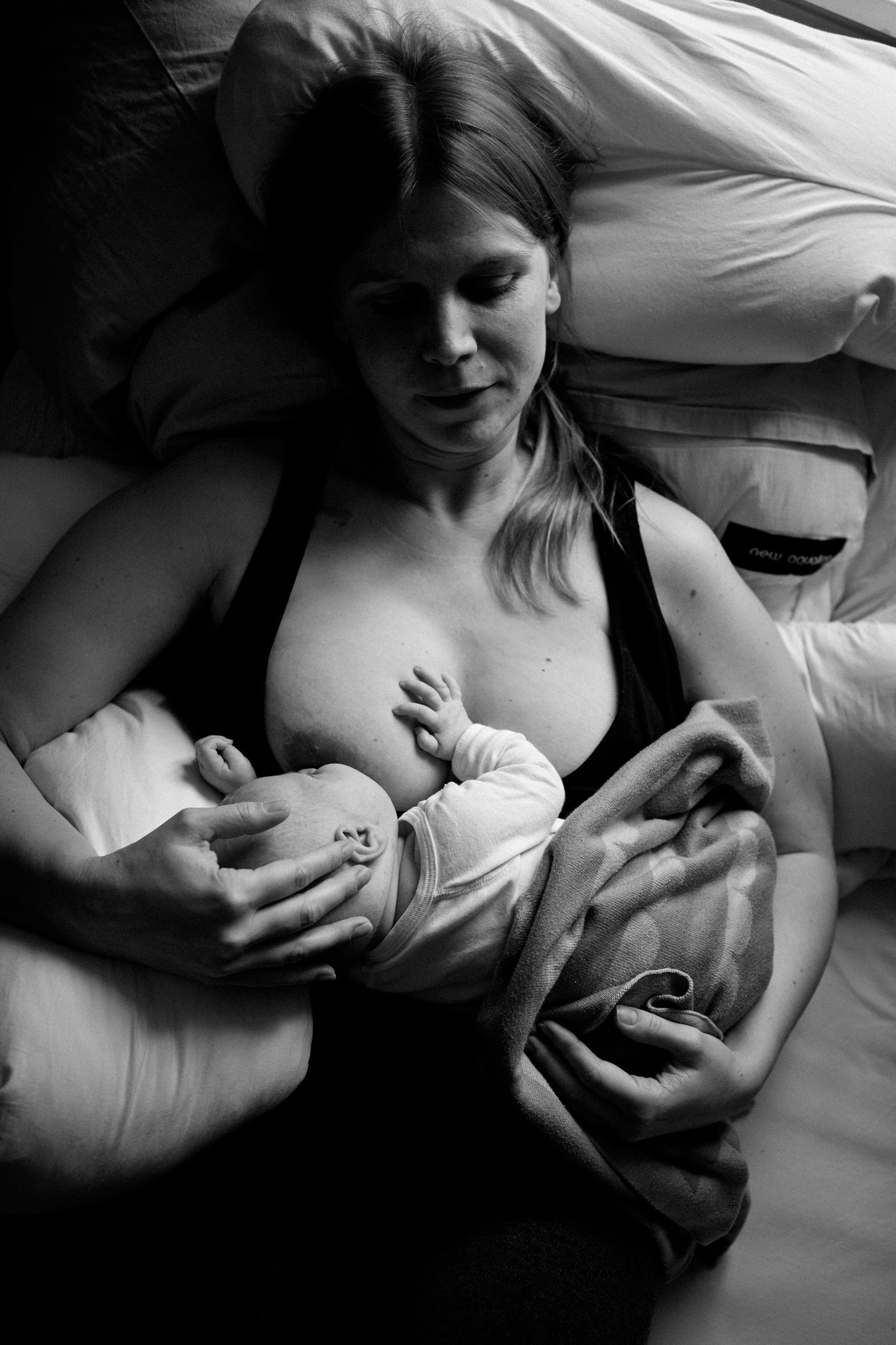 Neugeborenenfotos Berlin _ Mama stillt Baby im Bett schwarz-weiß