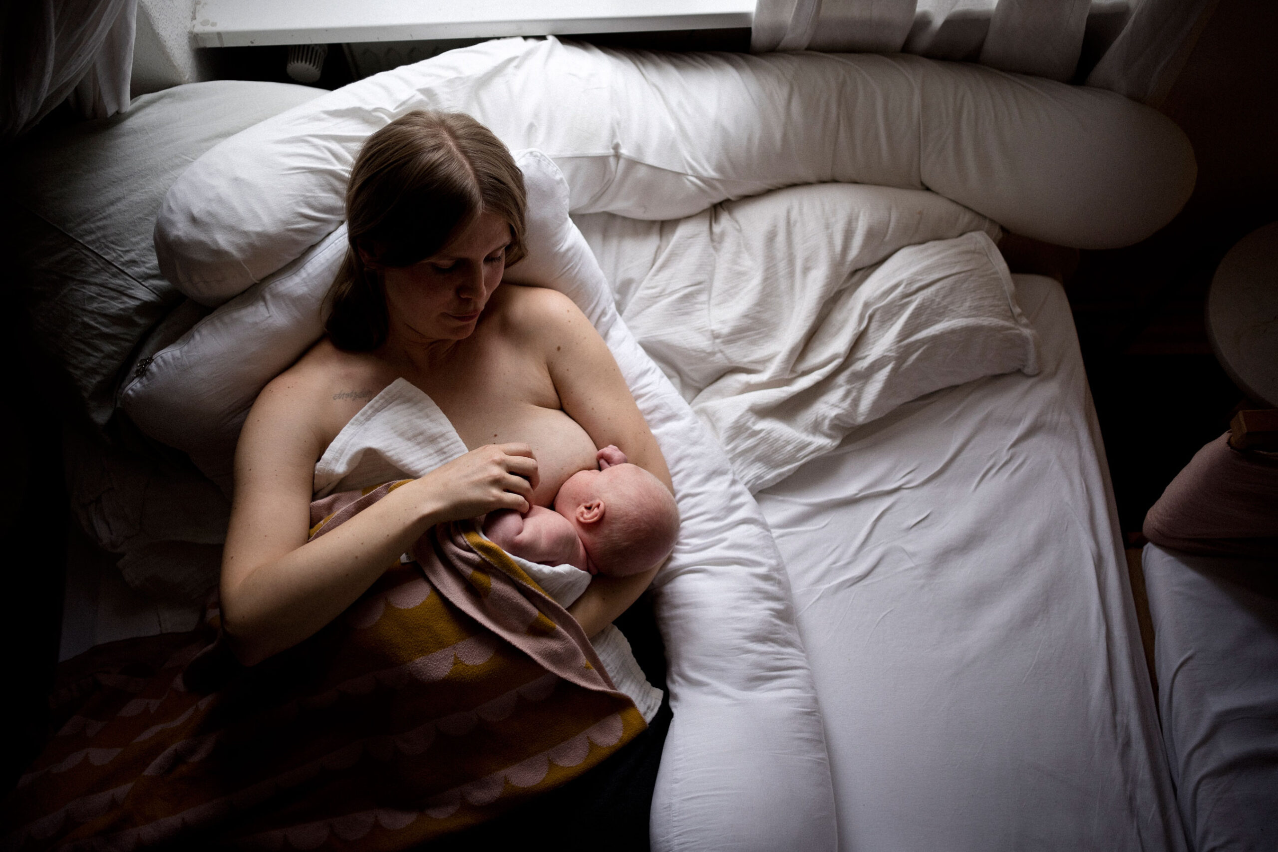 Wochenbettreportage stillende Mama mit Baby im Bett