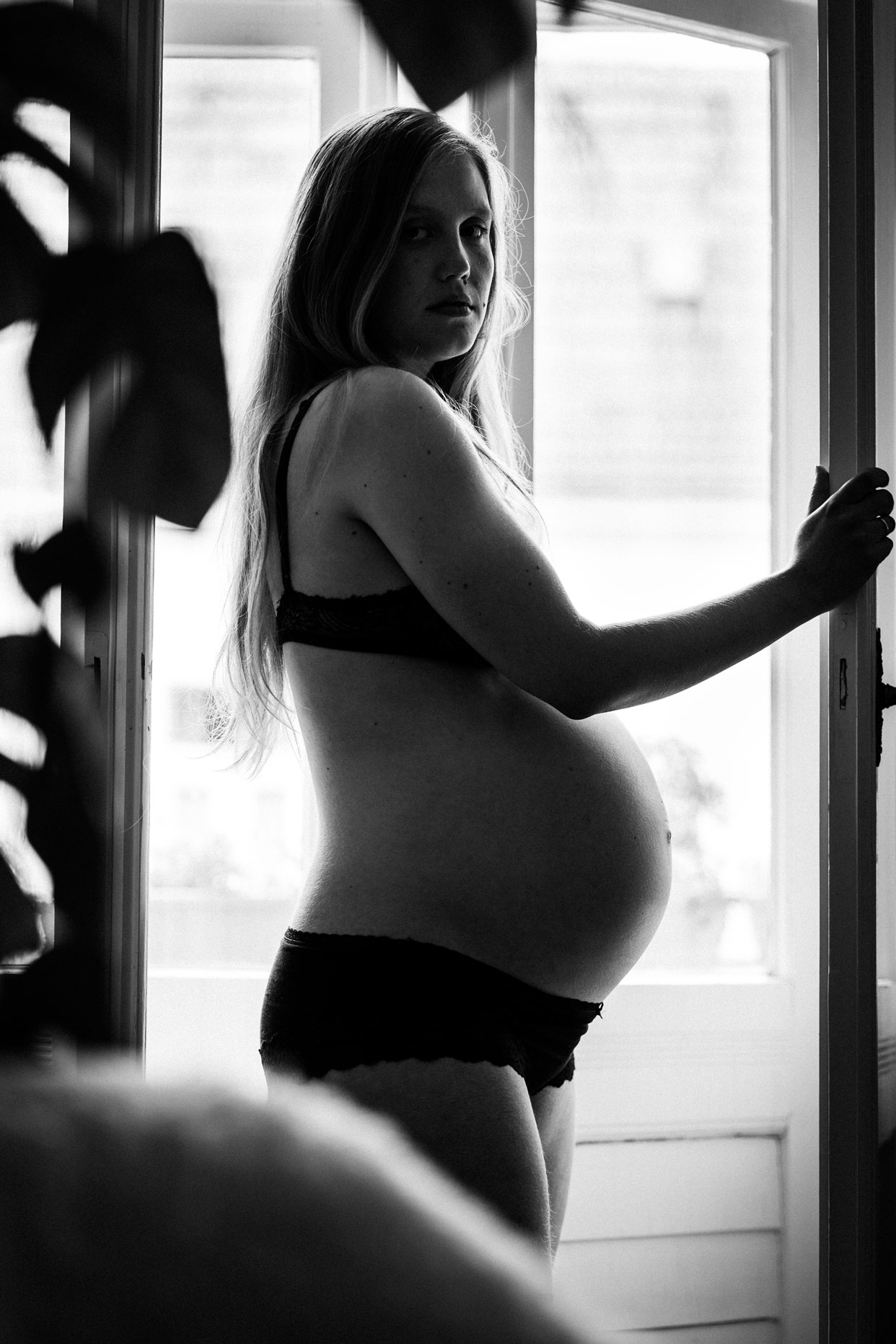 Schwangerschaftsfotos Zuhause Berlin_Schwangere in Unterwäsche vor Balkontür_schwarz-weiß